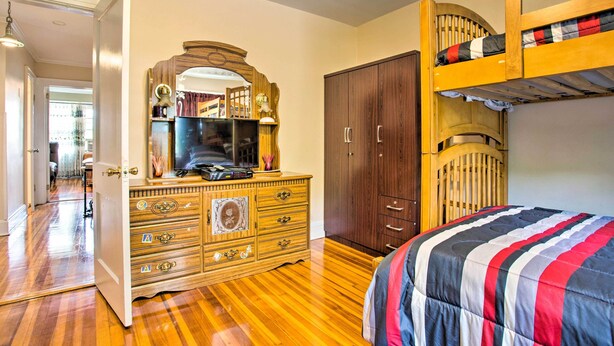 A bedroom with a bunk bed, wooden dresser, and a vanity with a mirror. - Charming Yonkers Retreat - 10 Mi to Central Park! (Yonkers)