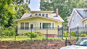 A yellow house with a brick wall and a black metal fence in front. - Charming Yonkers Retreat - 10 Mi to Central Park! (Yonkers)