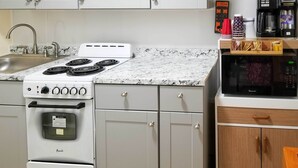 A kitchen with a white stove, a microwave, and a sink. - Charming Yonkers Retreat - 10 Mi to Central Park! (Yonkers)