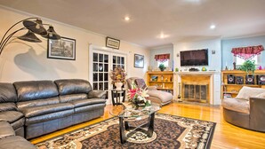 A living room with a leather sofa, a glass coffee table, and a fireplace. - Charming Yonkers Retreat - 10 Mi to Central Park! (Yonkers)