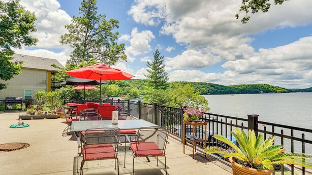 An outdoor patio with a table and chairs, a red umbrella, and a view of a lake. - 3 Cabins! Lakefront Reunion Retreat in Rocky Mount (Rocky Mount)