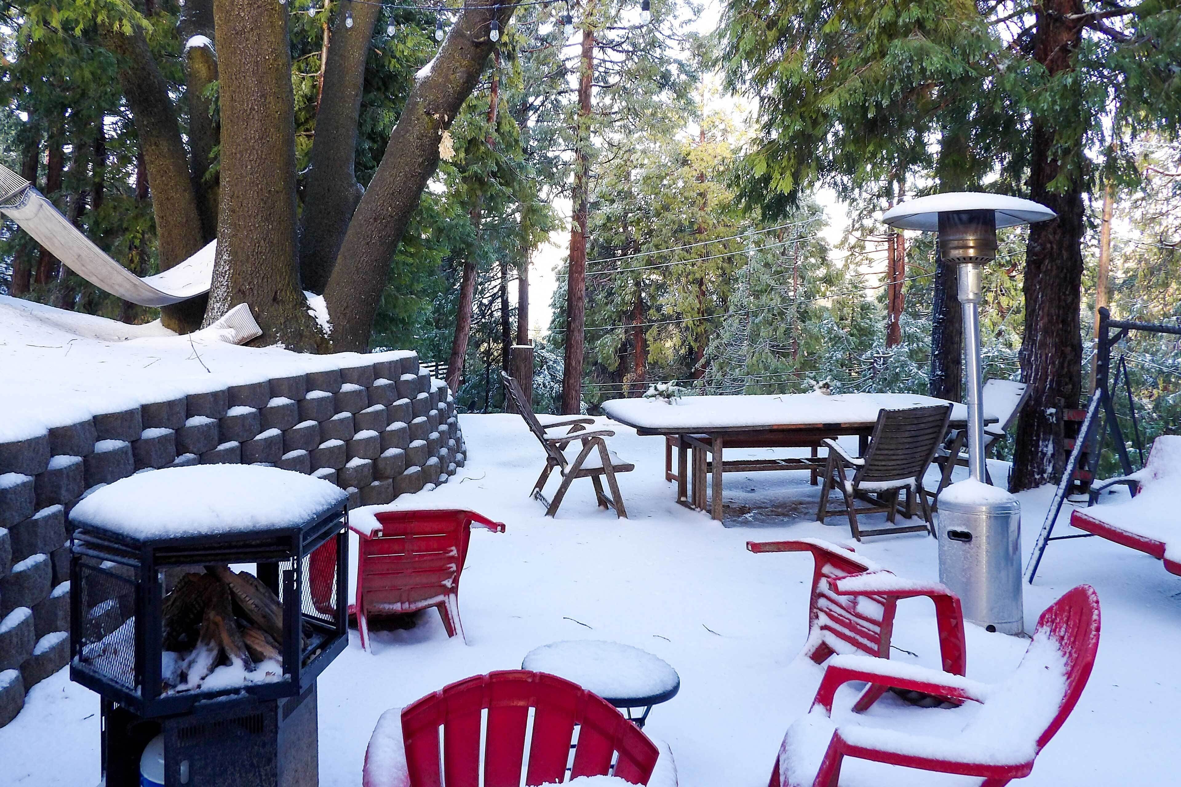 Un espace extérieur aménagé avec des meubles de jardin, recouvert de neige, comprenant une table, des chaises et un foyer.