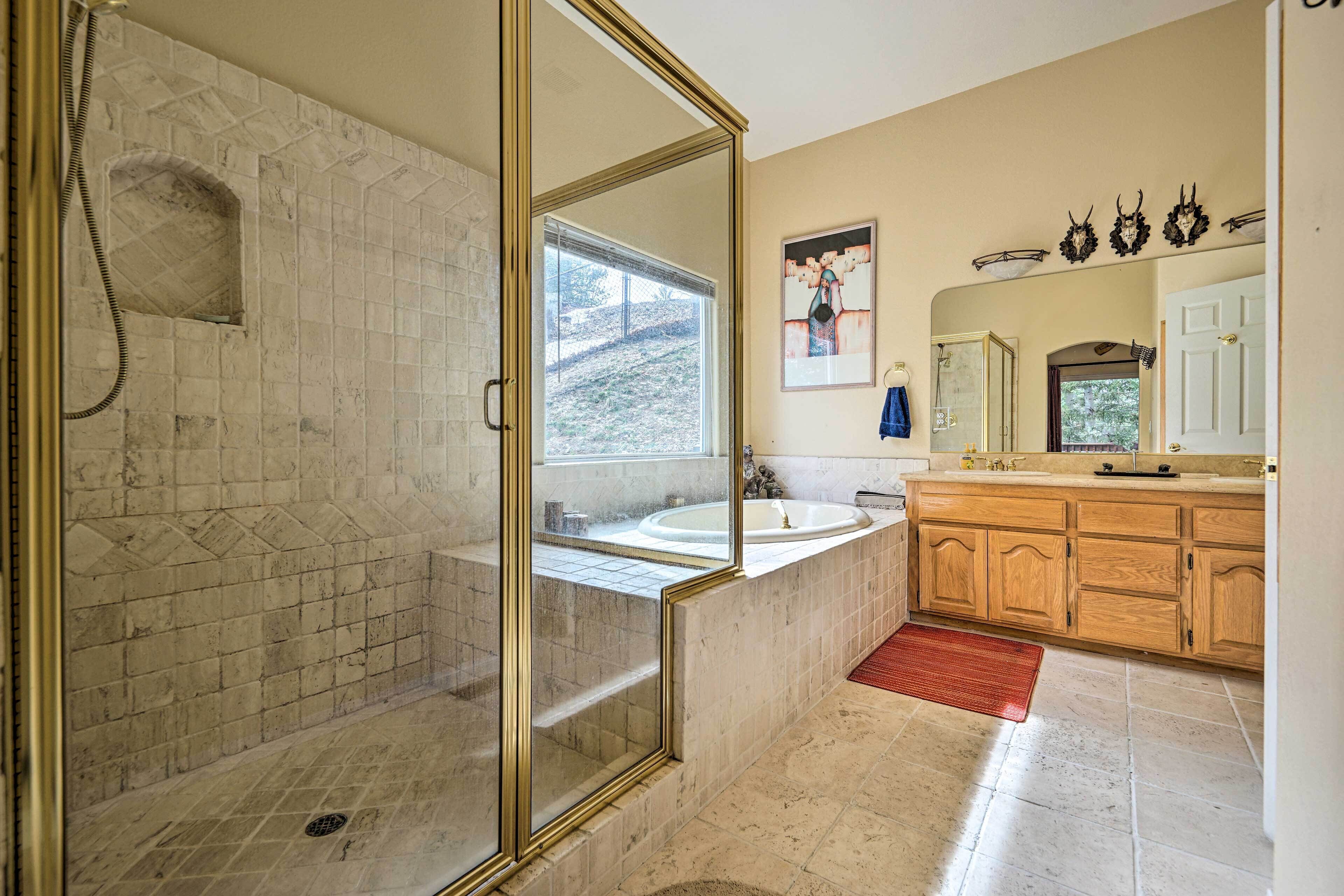 A bathroom with a glass-enclosed shower, a sink, and wooden cabinets.