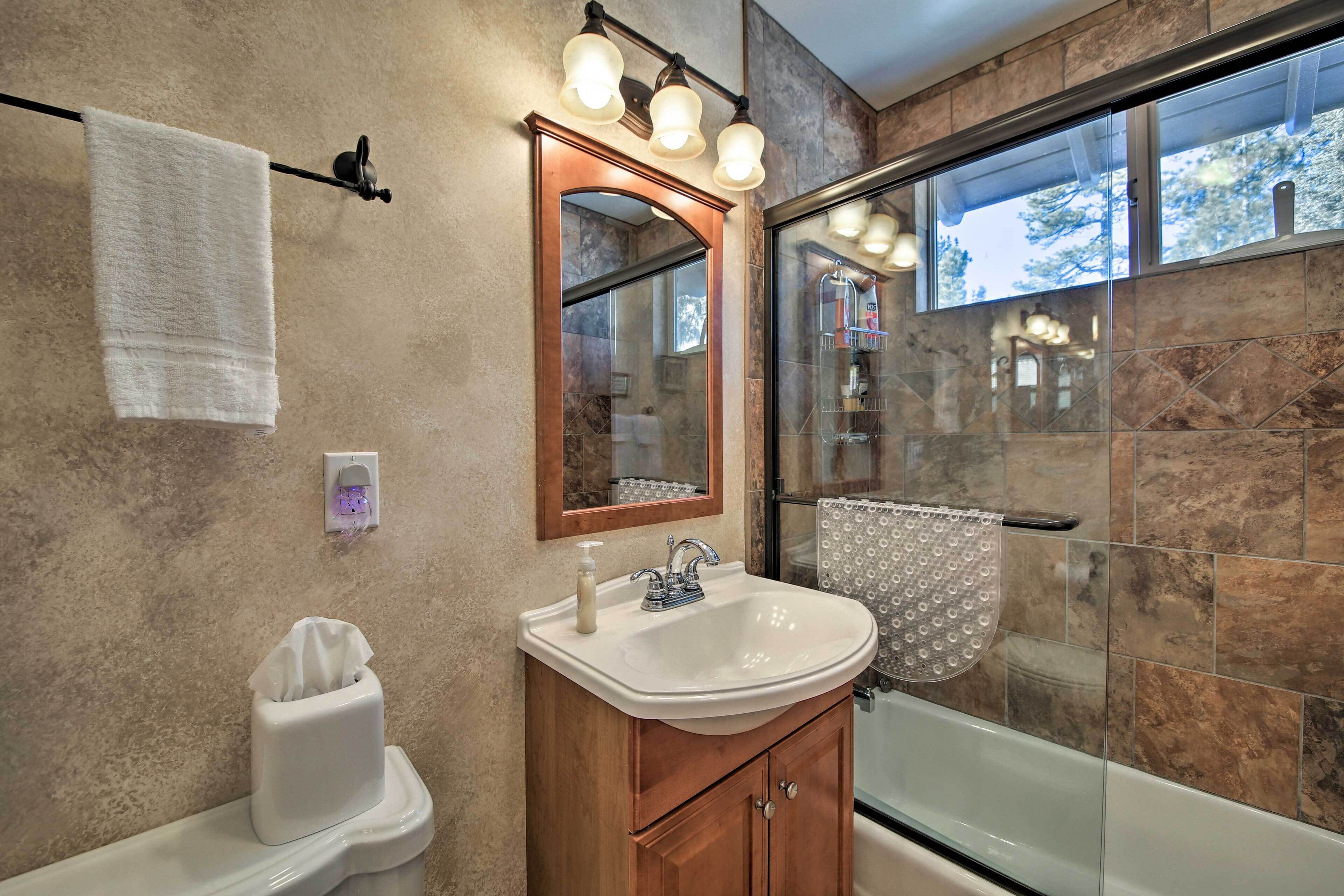 A bathroom with a white sink, wooden vanity, and a glass shower enclosure.