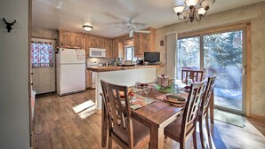 A spacious kitchen with wooden cabinets, a central island, and a dining area with chairs and a table. - Walk to Lake: Rustic Home w/ Deck in Fawnskin (Fawnskin)