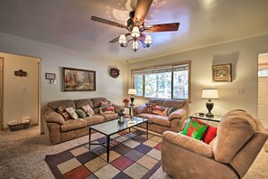 A living room with two couches, a coffee table, a ceiling fan, and a large window. - Walk to Lake: Rustic Home w/ Deck in Fawnskin (Fawnskin)