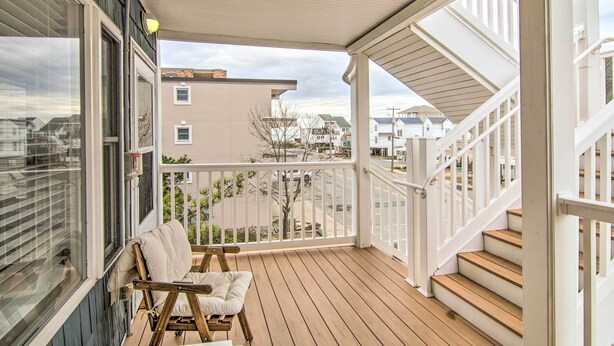 A wooden deck with a white railing, a bench, and a view of neighboring houses. - Walk to Maryland Beach: Coastal Condo w/ Balcony (Ocean City)