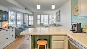 A modern kitchen with a central island, white cabinetry, and pendant lighting. - Walk to Maryland Beach: Coastal Condo w/ Balcony (Ocean City)