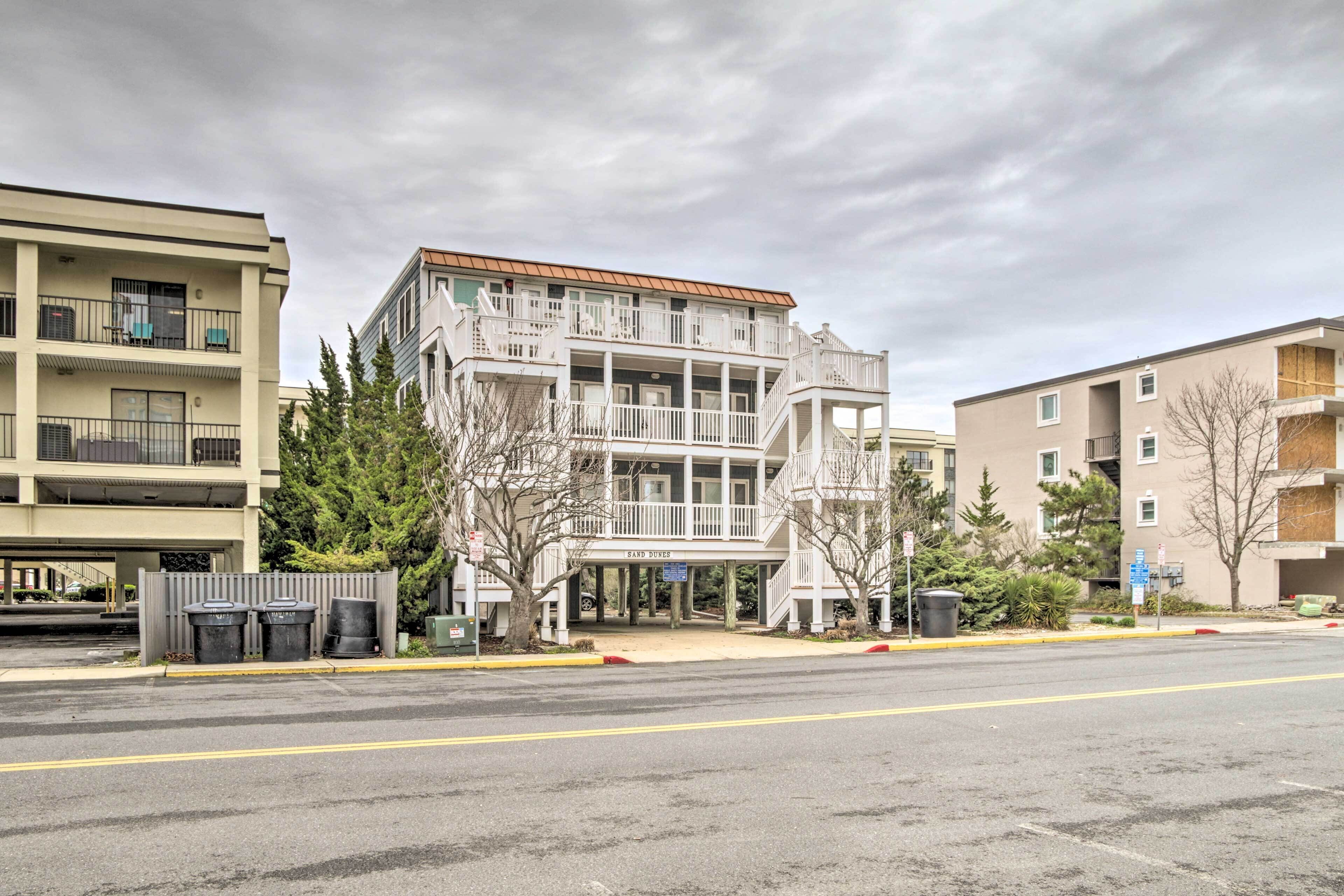 A multi-story building with balconies, a covered entrance, and a sign that reads "Sand Dunes."