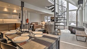 A modern interior with a dining area, kitchen, and living space, featuring a spiral staircase and large windows. - Vail Condo w/ Mtn-view Deck - Steps to Ski Shuttle (Vail)