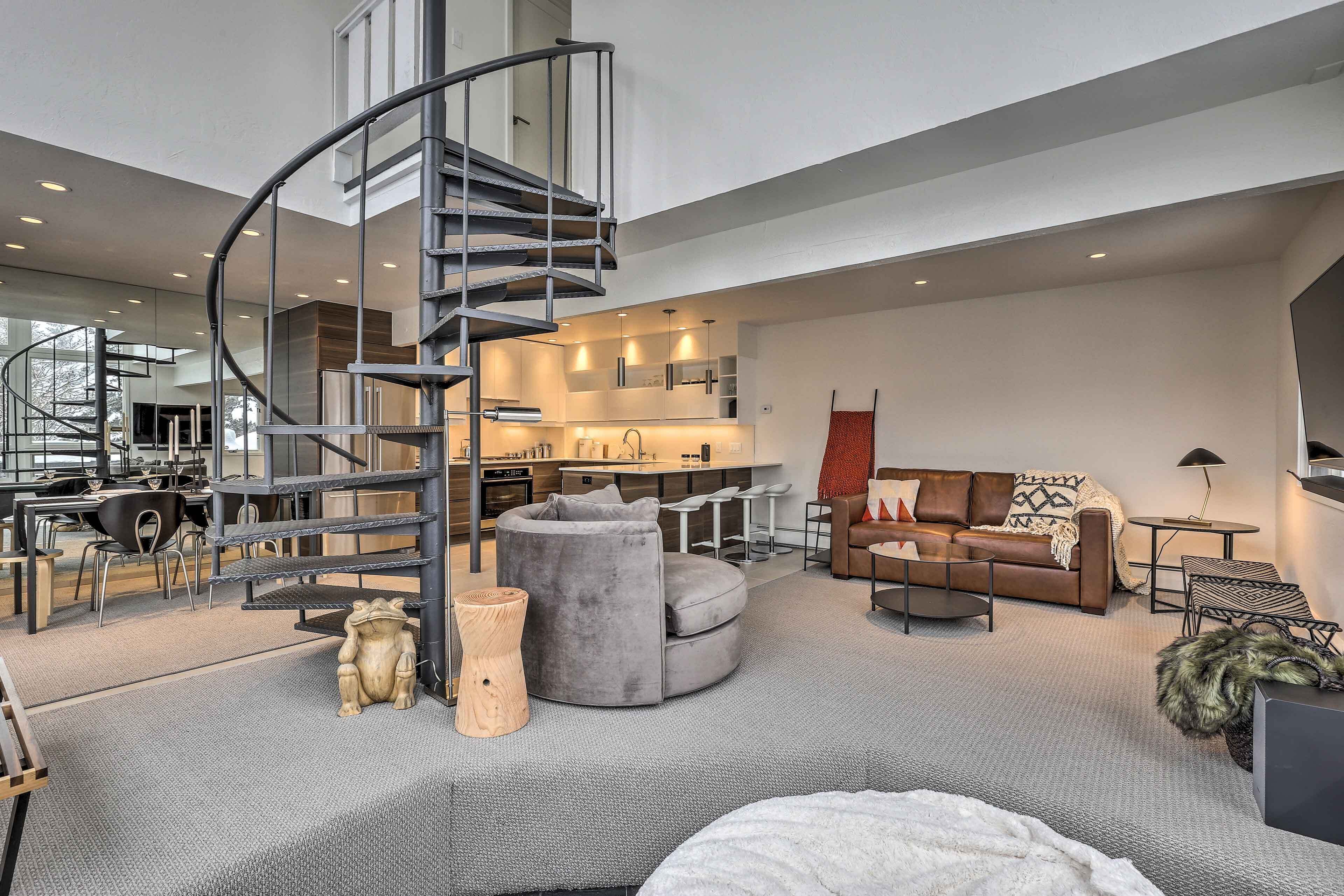 A modern interior with a spiral staircase, a cozy seating area, and a kitchen in the background.
