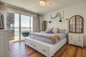 A bedroom with a large bed, a dresser, a nightstand, and a view through a glass door. - Furnished Porch, Resort Pools! Lands End Condo (Osage Beach)