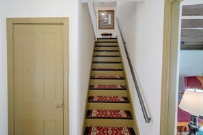 A staircase with a wooden handrail and red patterned carpet. - 4BR Group Getaway on the Chickley River (Charlemont)