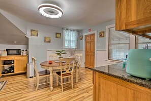 A compact kitchen with wooden cabinets, a dining table with chairs, a microwave, and a sink. - Boston Area Hub By Train Station, Gillette Stadium (Stoughton)