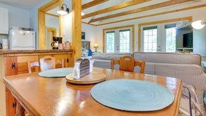 Une cuisine spacieuse avec des poutres en bois, une table à manger avec des sets de table et, au fond, un canapé à rayures.