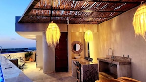 Un baño al aire libre con diseño moderno, que cuenta con un espejo grande, dos lavamanos e iluminación colgante.
