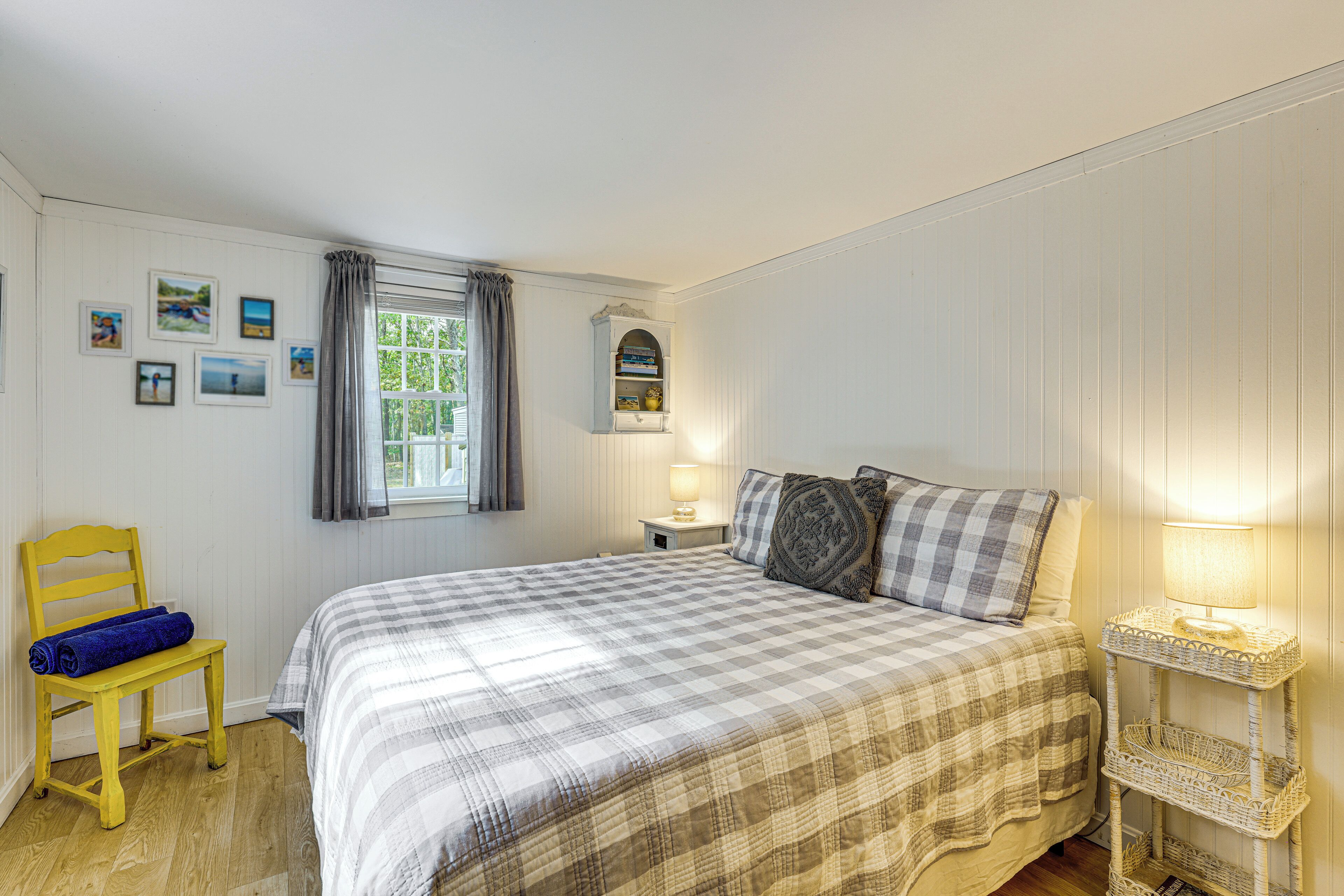 A bedroom with a bed, a chair, a nightstand, and a window with curtains.