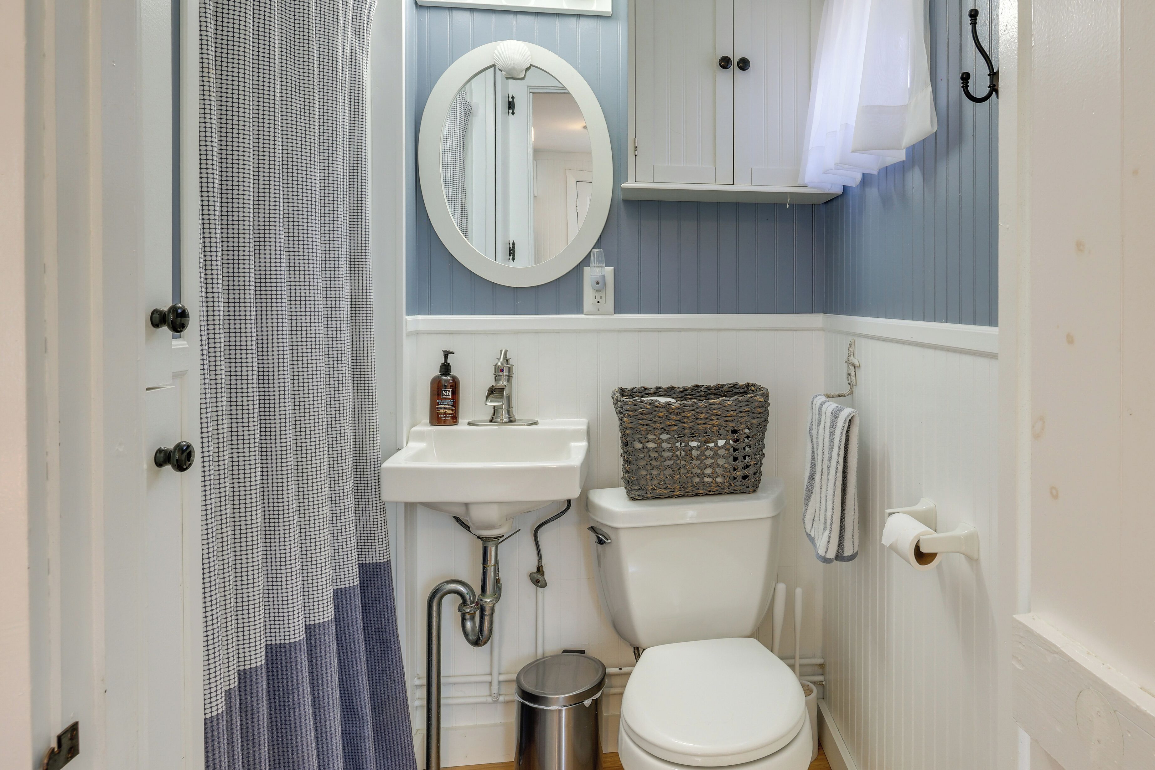 Een badkamer met een wit wastafel, toilet, spiegel en douchegordijn.