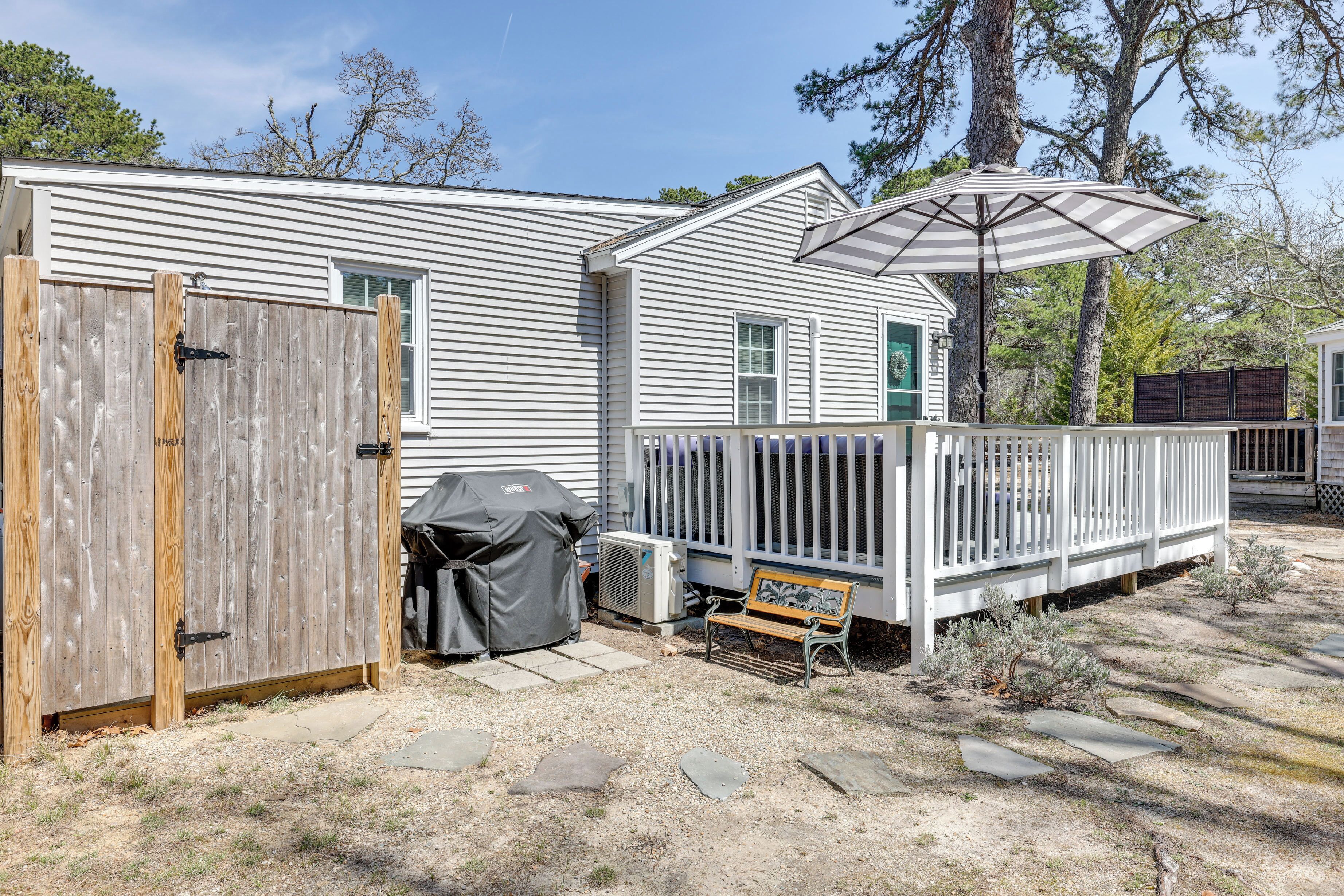A residential property with a fenced backyard, a covered grill, a bench, and a white deck.