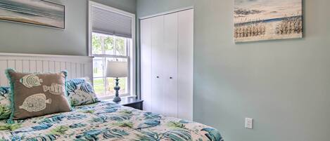 A bedroom with a bed, a window, a closet, and a painting on the wall.
