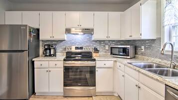 Una cocina moderna con electrodomésticos de acero inoxidable, armarios blancos, una encimera de granito y una ventana con vistas.