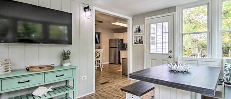 Une cuisine avec un plancher en bois, une table à manger et un téléviseur fixé au mur.