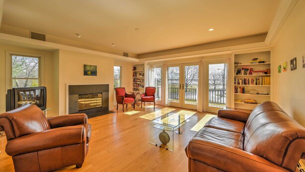 A living room with a fireplace, leather sofas, a glass coffee table, and a bookshelf. - Multi-level Marion House: Loft, Deck + Ocean Views (Marion)