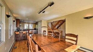 A spacious dining area with a large wooden table and multiple chairs, a kitchen in the background, and a staircase leading to another level. - Multi-level Marion House: Loft, Deck + Ocean Views (Marion)