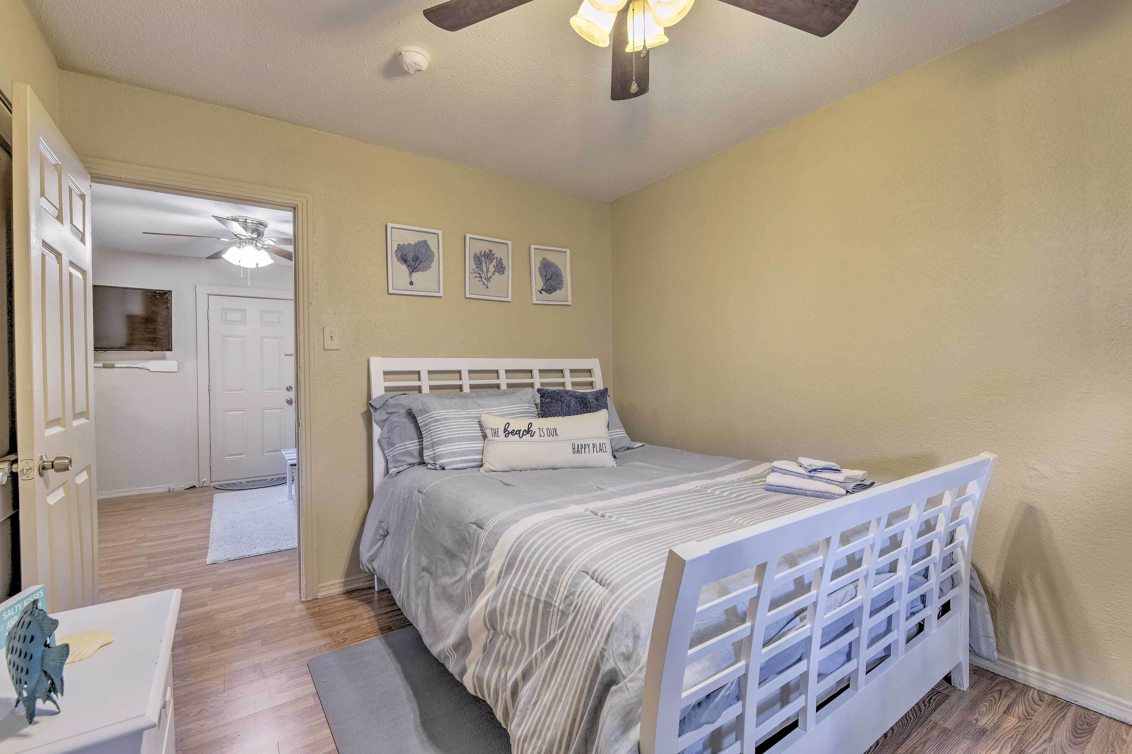 Un dormitorio con cama, ventilador de techo y puerta que da a otra habitación.