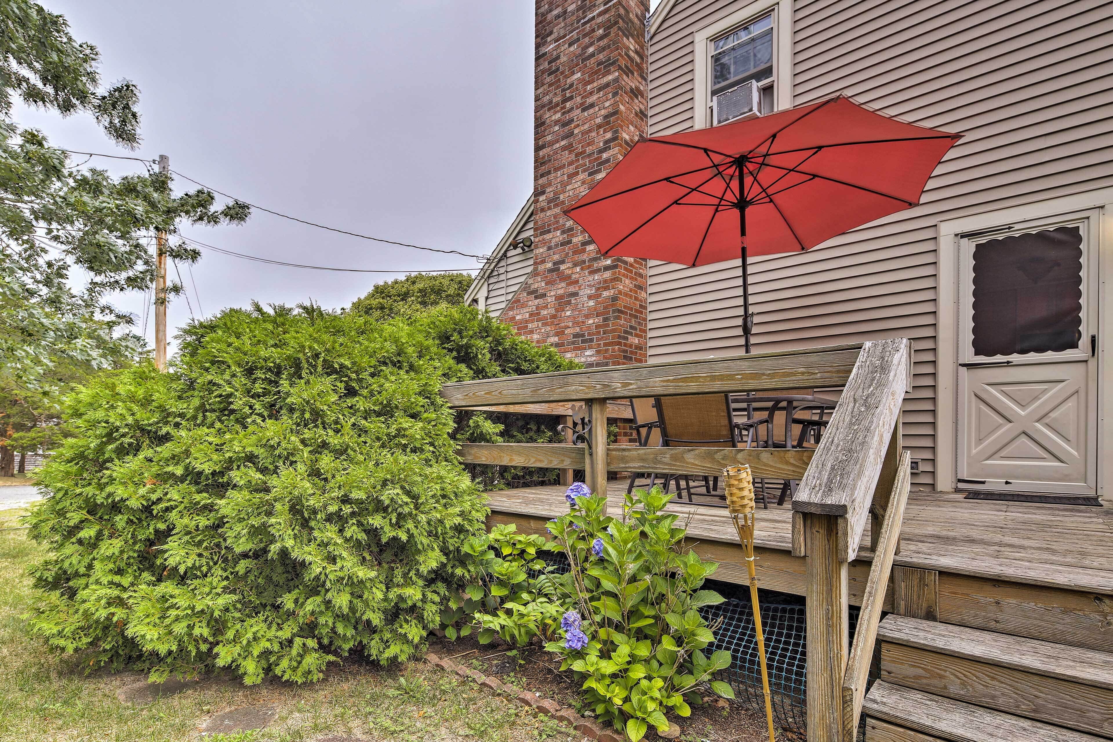 A wooden deck with a red umbrella, a brick chimney, and a wooden fence.