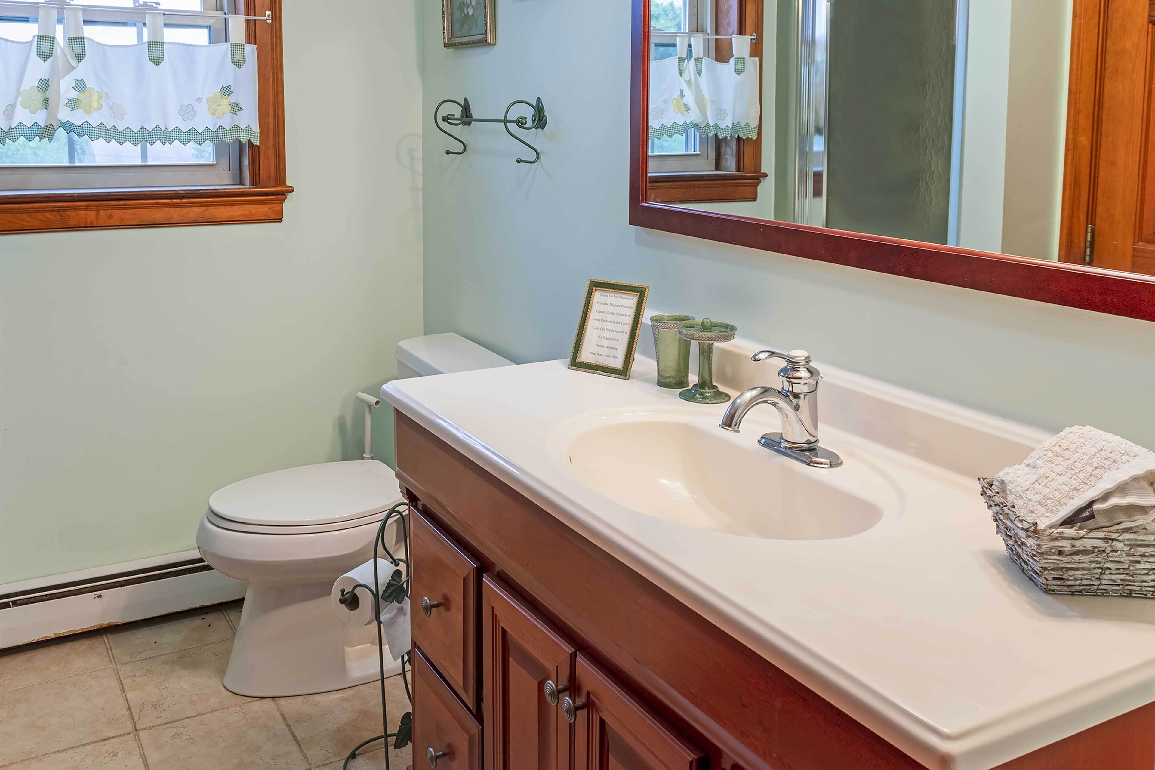A bathroom with a white sink, vanity, and toilet.
