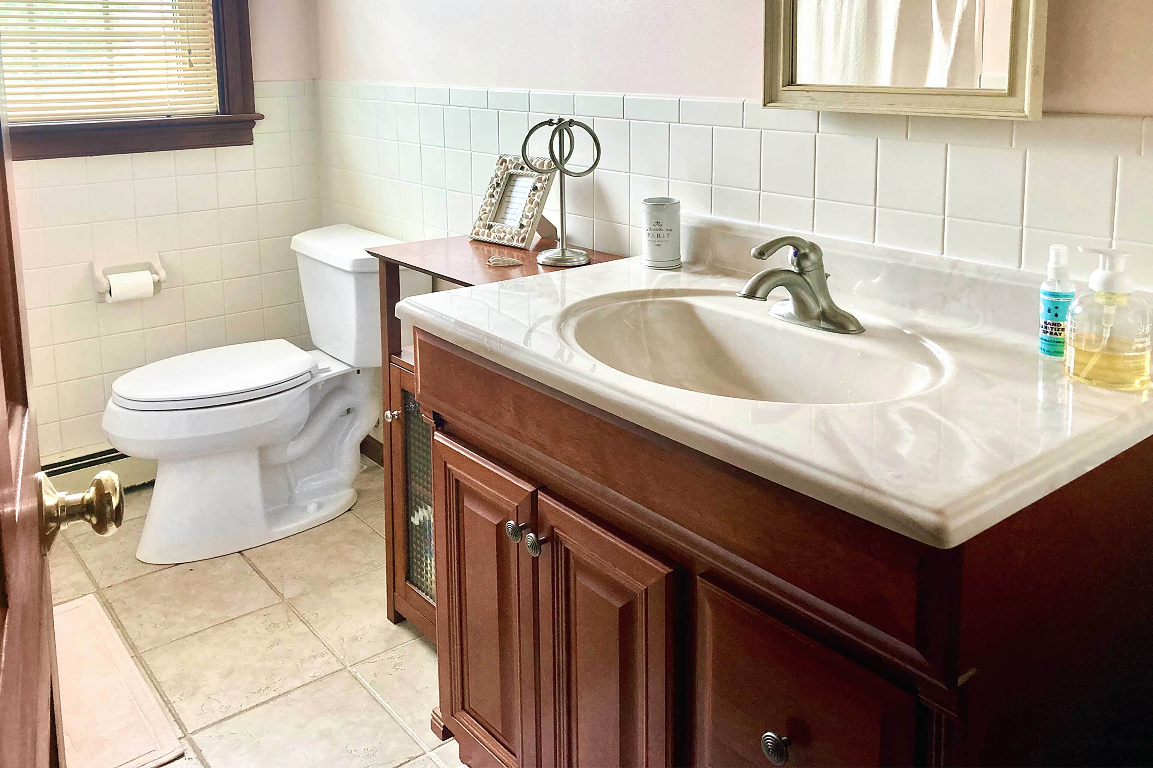 A bathroom with a white toilet, a sink with a mirror above it, and a towel rack.