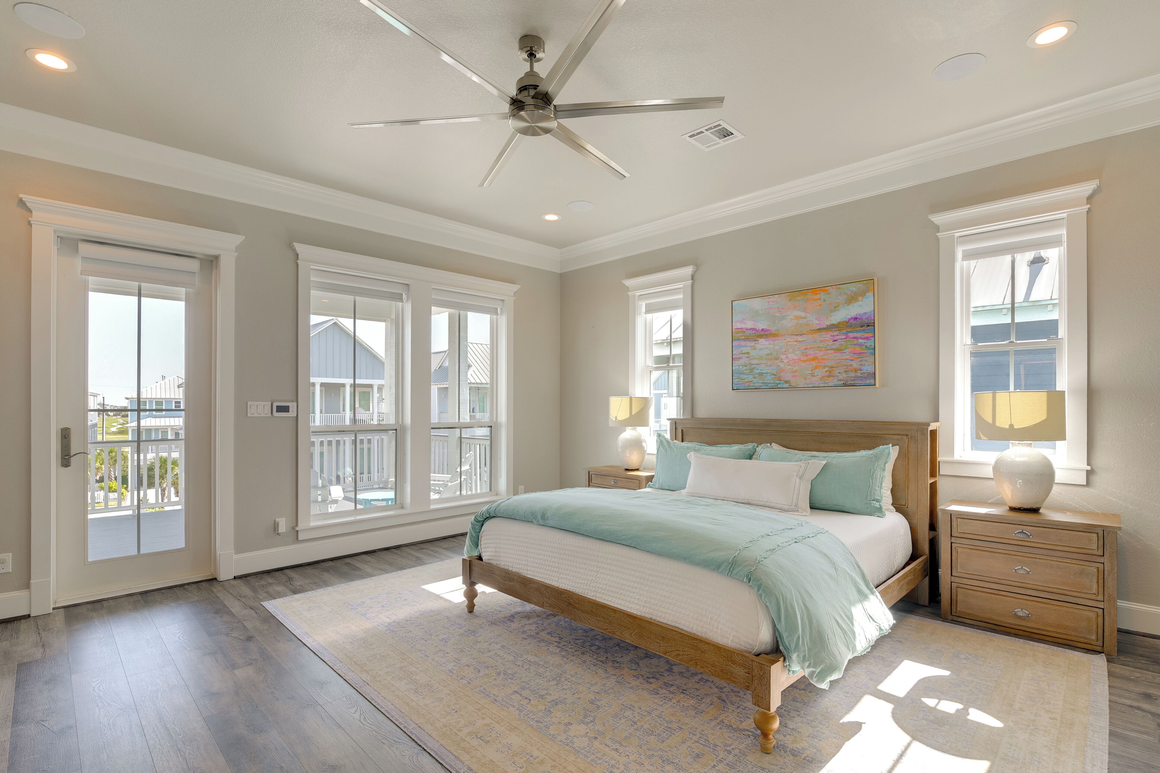 Une chambre avec un grand lit, un ventilateur de plafond et une vue sur l’extérieur.
