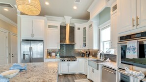 A modern kitchen with white cabinetry, stainless steel appliances, and a granite countertop.