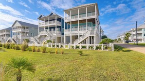 A beachfront property with multiple-story buildings, balconies, and a white fence.