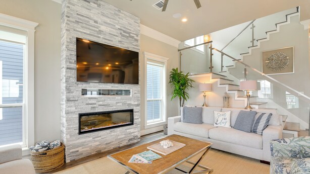 A modern living room with a stone fireplace, a staircase, and a cozy seating area.