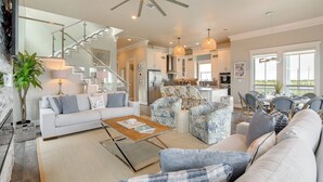 A spacious living area with a modern kitchen, a staircase, and a dining area with outdoor views.