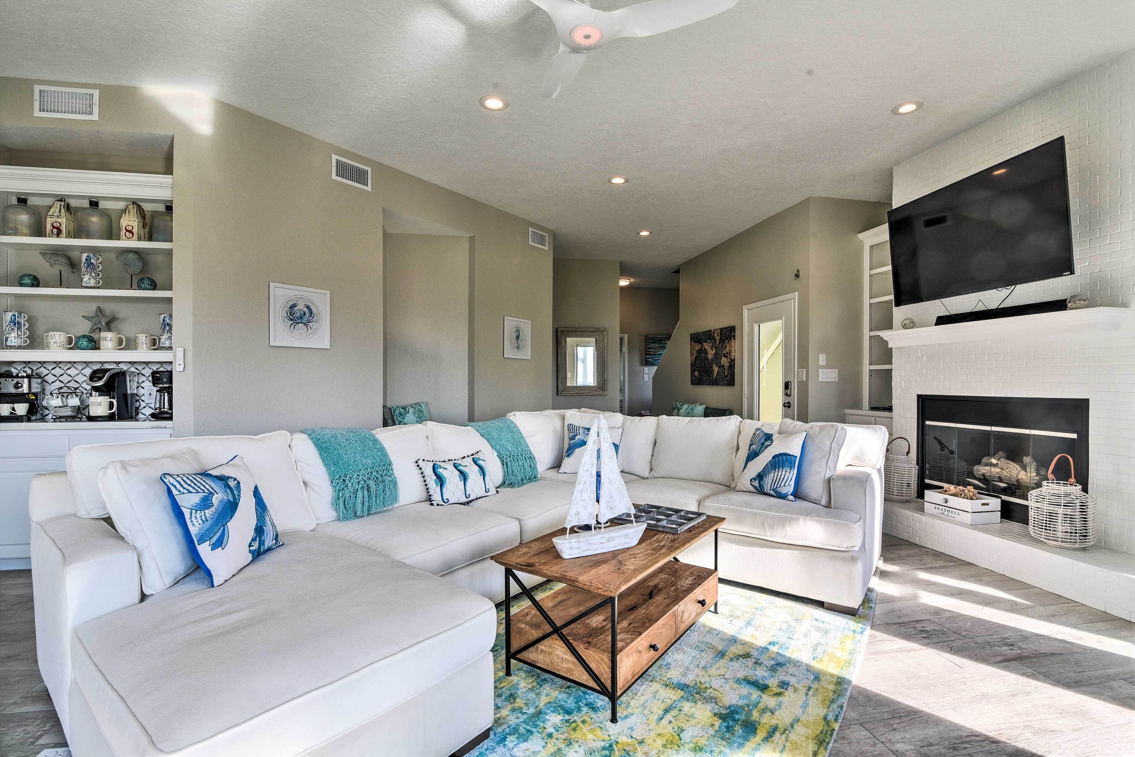 A modern living room with a sectional sofa, a coffee table, and a fireplace.