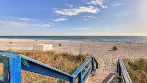 A wooden boardwalk leading to a sandy beach with a clear sky. - Resort Pool, Gym & Hot Tub: Beachfront PCB Condo! (Panama City Beach)