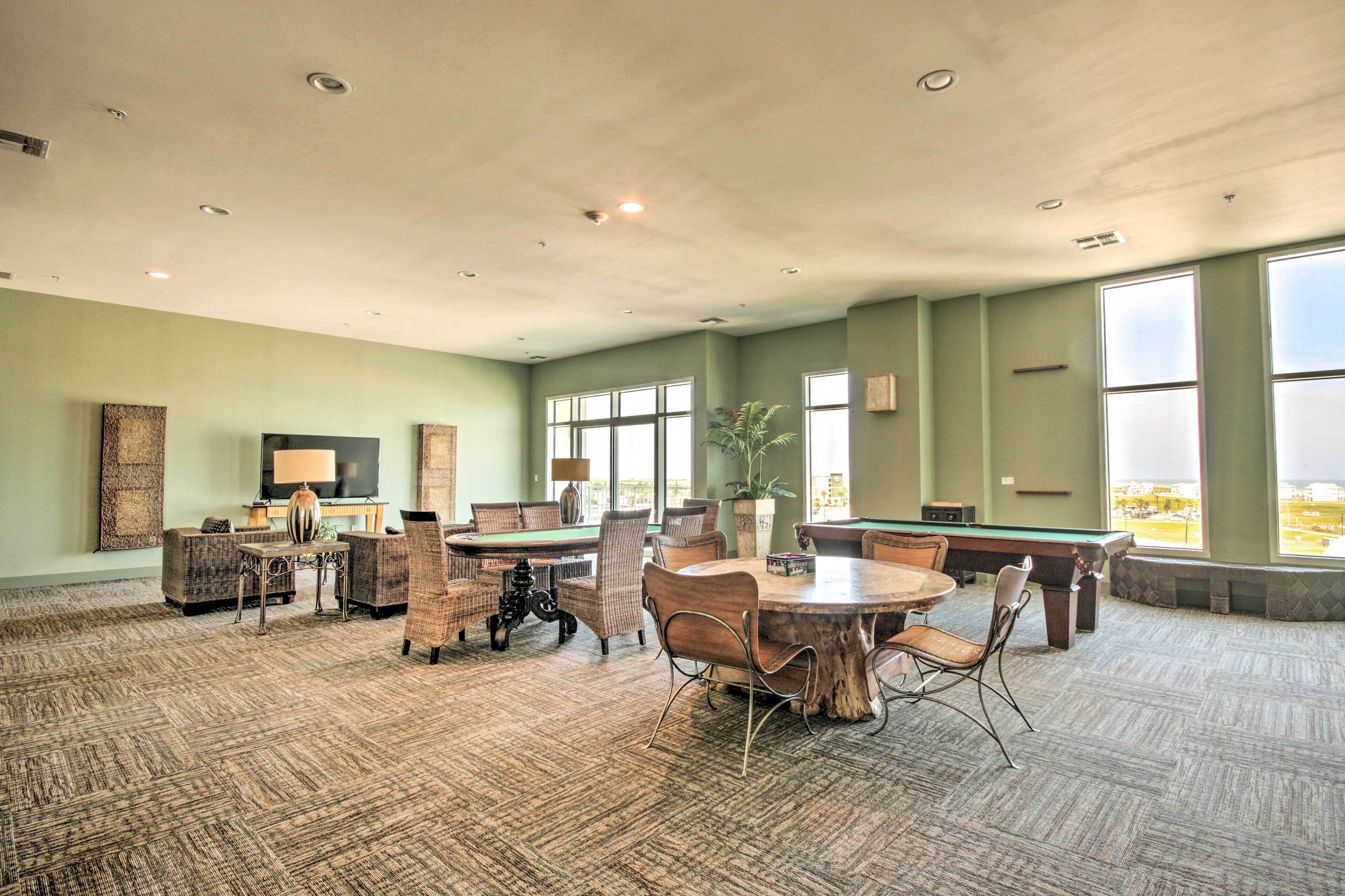 Una habitación amplia con mesa de billar, asientos cómodos y grandes ventanales con vistas.