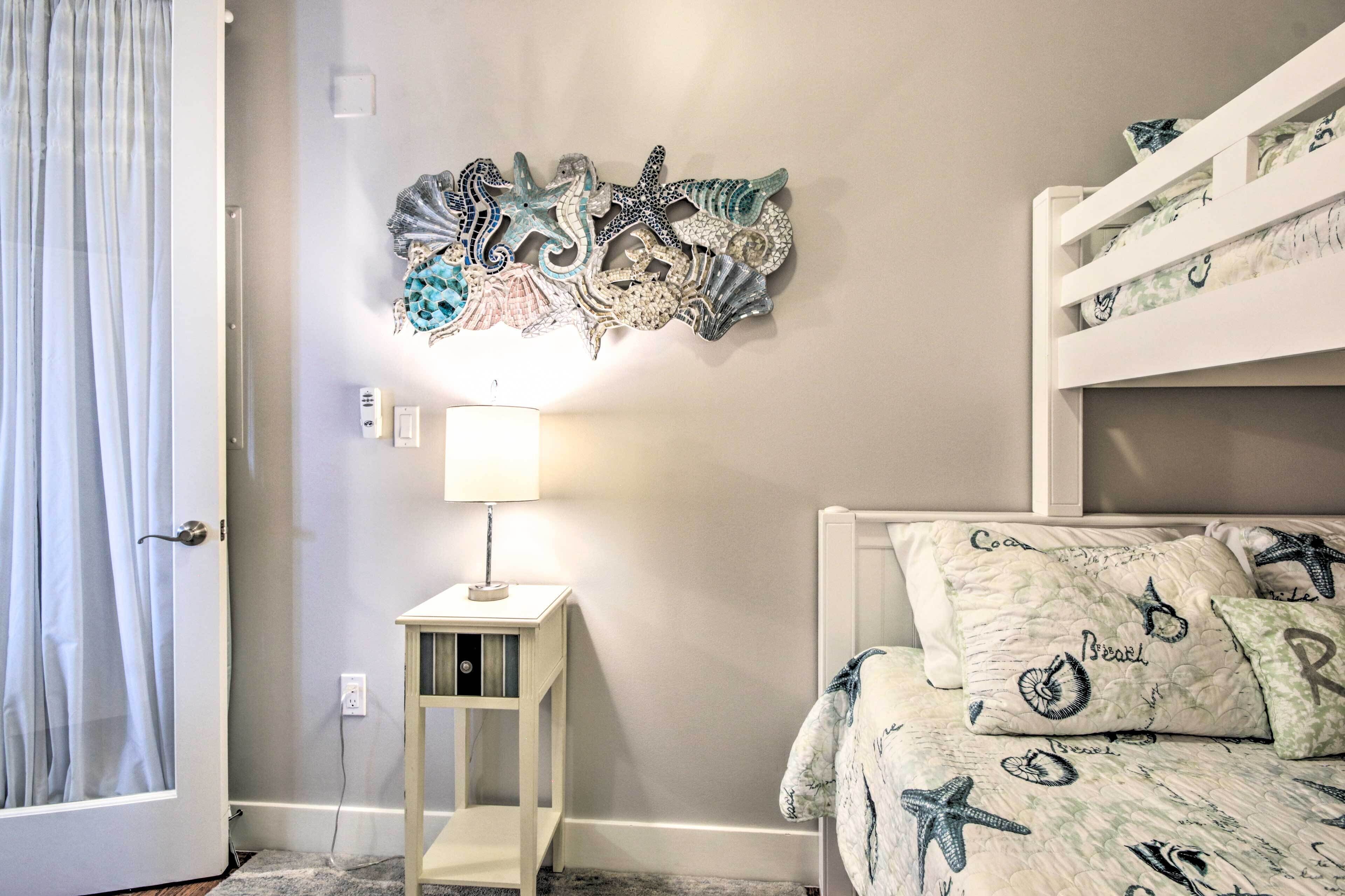 Quarto com uma cama beliche, uma mesa de cabeceira com abajur e uma decoração na parede.