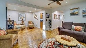 A spacious living room with hardwood flooring, a ceiling fan, and a brown sofa with decorative pillows.