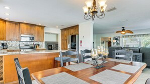 A spacious kitchen with wooden cabinets, a central island, and a dining area with a wooden table and chairs. - Spacious Canalfront Home w/ Pool ~ 1/2 Mi to Beach (Hudson)