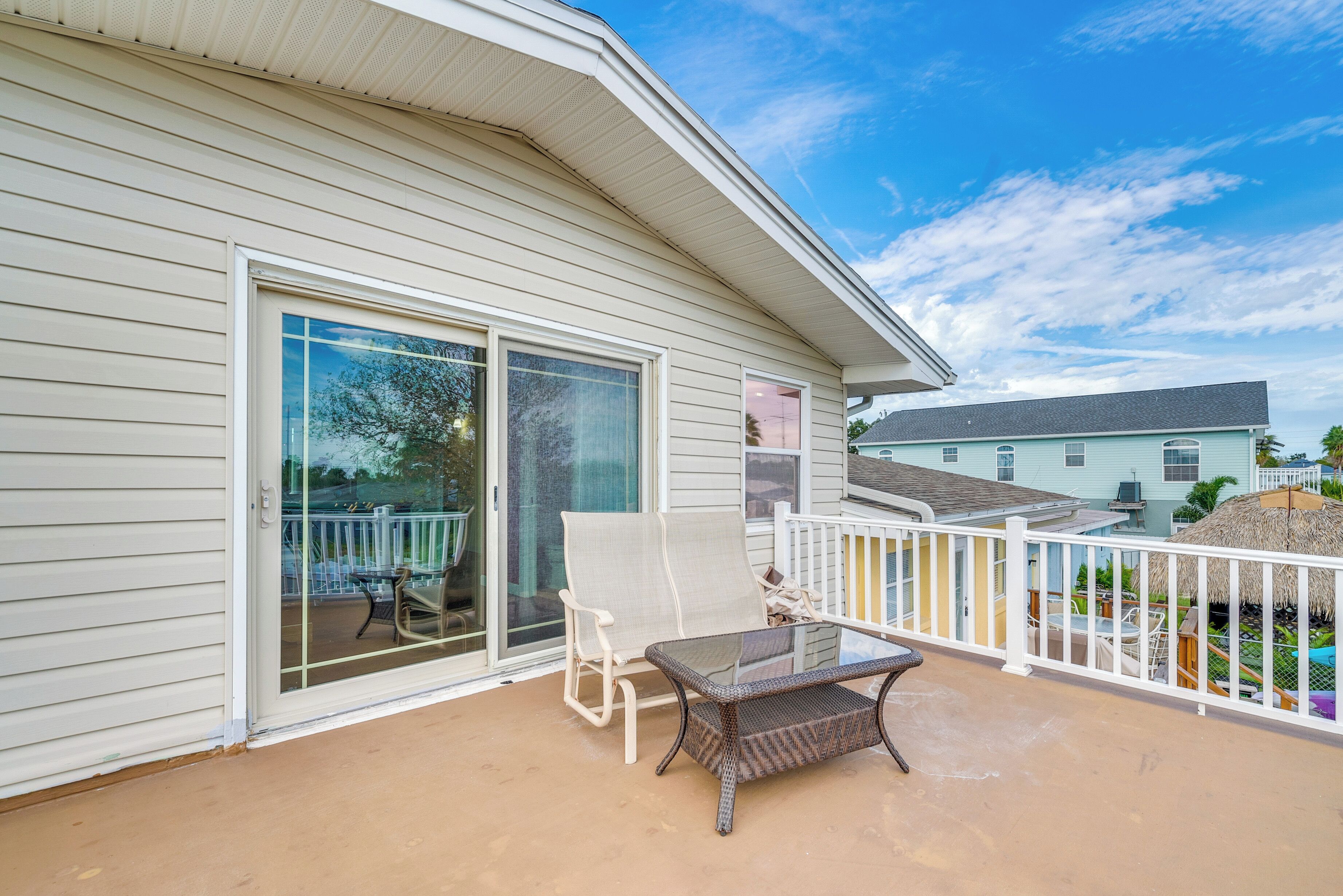 A covered patio with a sliding glass door, a wicker table, and two chairs.