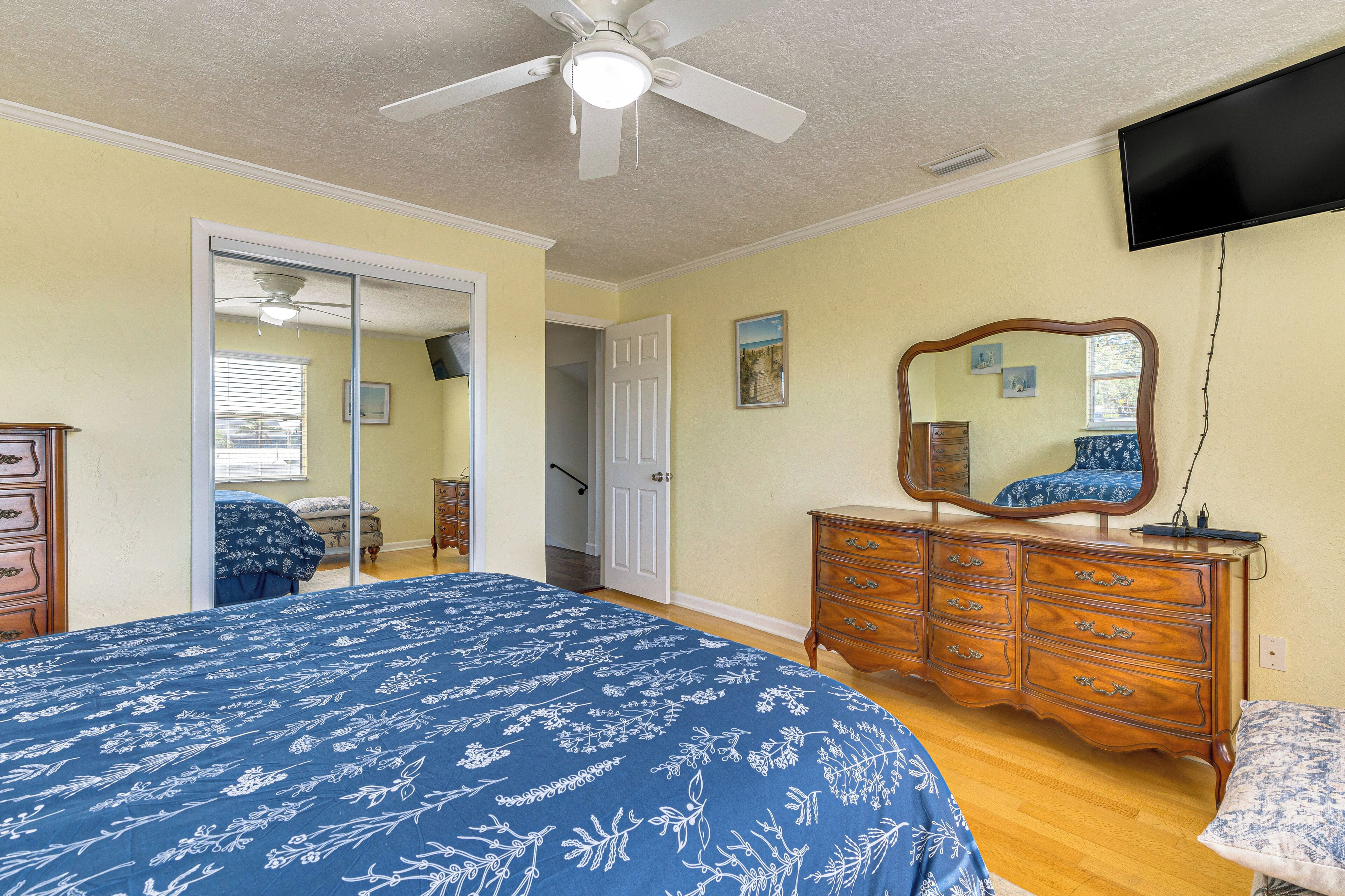 A bedroom with a bed, dresser, mirror, and a ceiling fan.