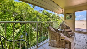 A balcony with wicker furniture and a view of lush greenery.