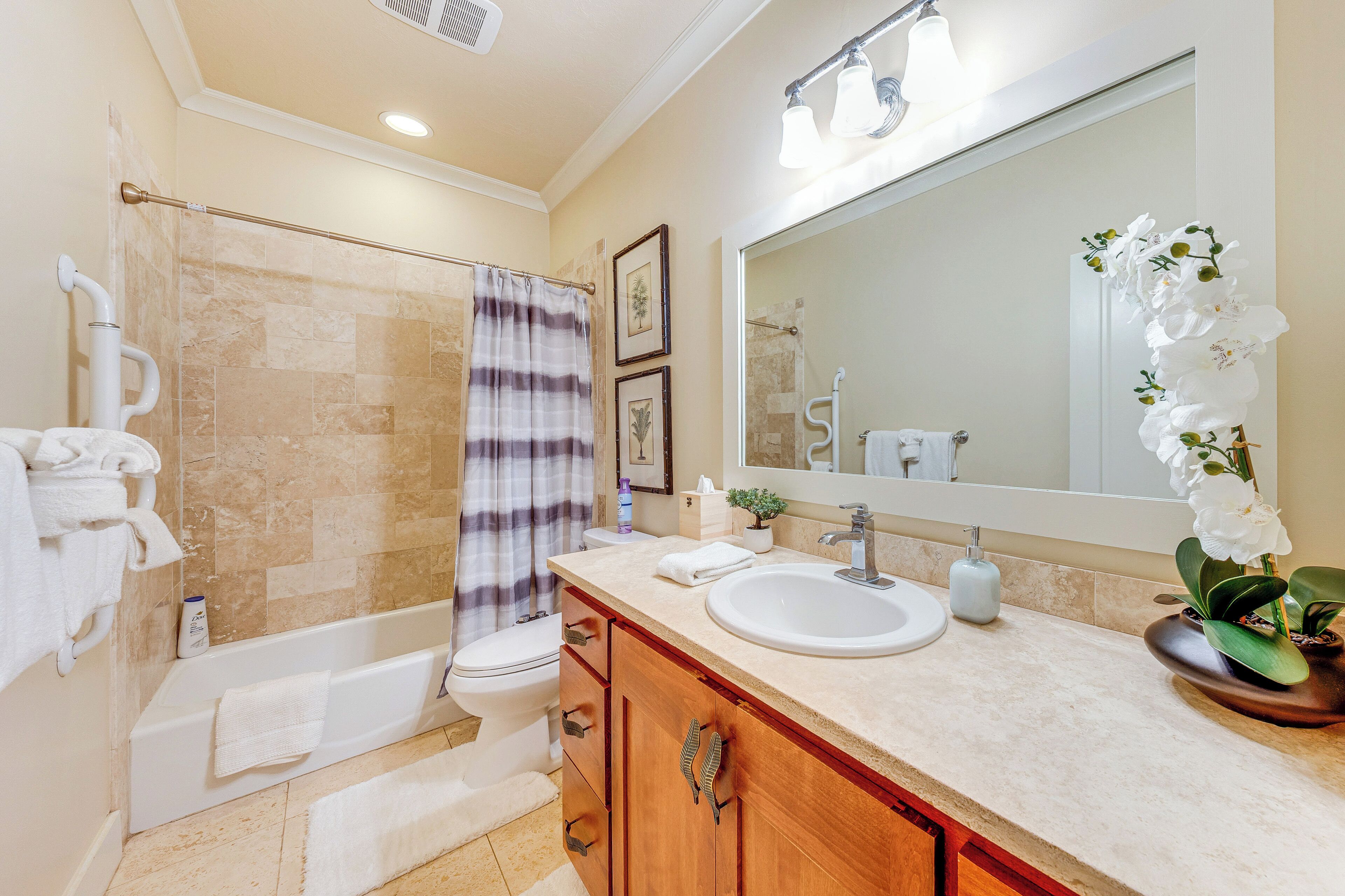 A bathroom with a shower, toilet, sink, and vanity.