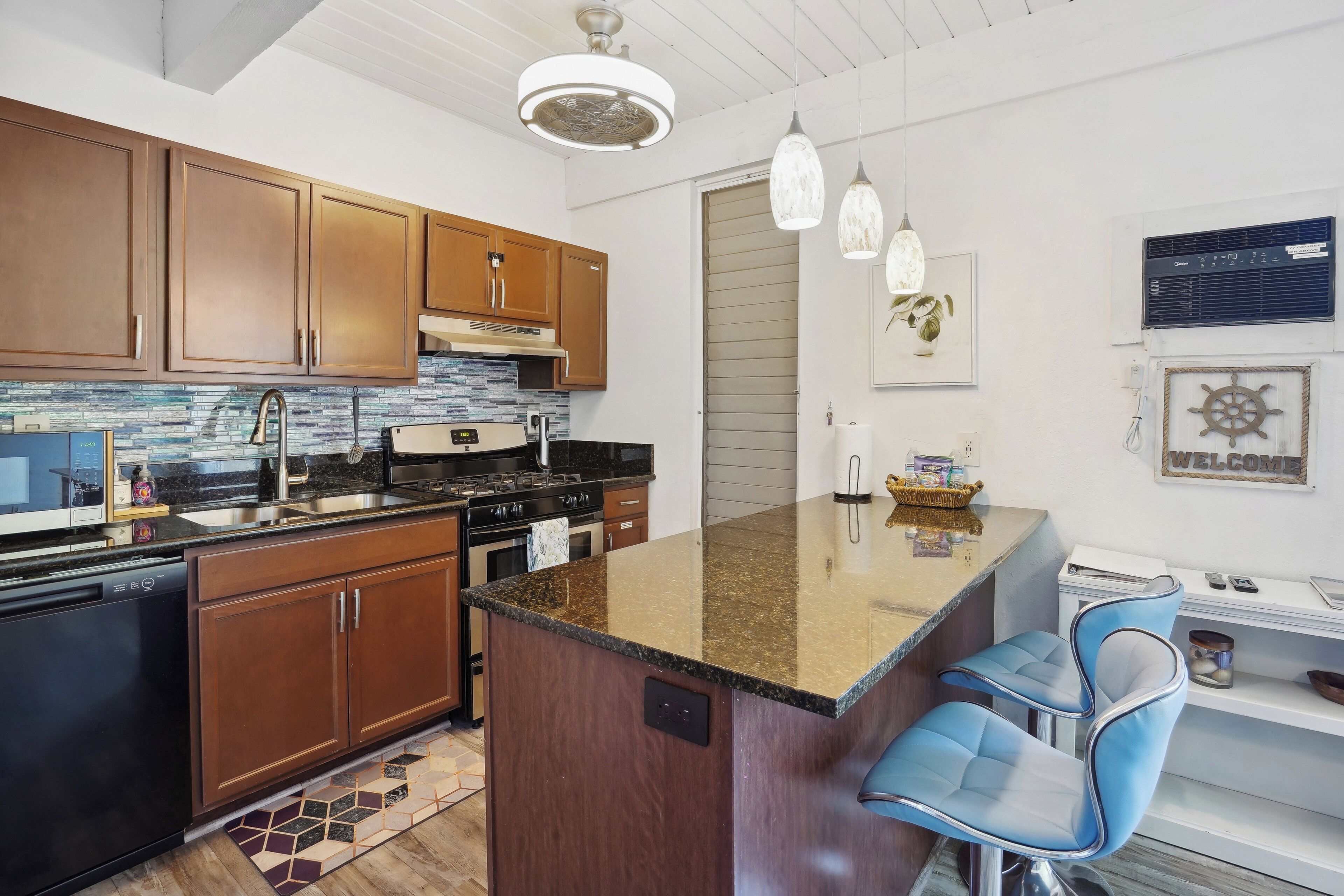 Una cocina moderna con armarios de madera, encimera de granito y una isla integrada con taburetes de bar.