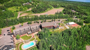 An aerial view of a resort with multiple buildings, a swimming pool, and surrounding forested areas. - Ski-in/ski-out Lutsen Retreat w/ Pool Access! (Lutsen)