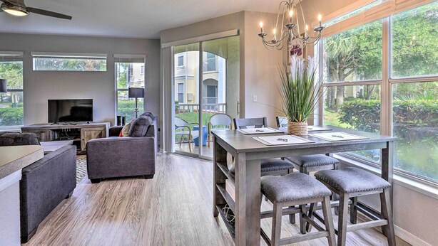 Una cocina moderna con comedor, ventanas amplias y vistas a un edificio residencial.